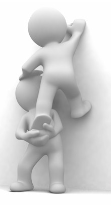 Zwei Personen machen die 'Räuberleiter', um eine Mauer hochzuklettern.